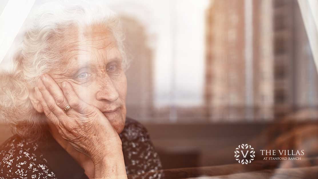 A senior looking sadly out a window. Learn more about fighting isolation and loneliness in seniors.