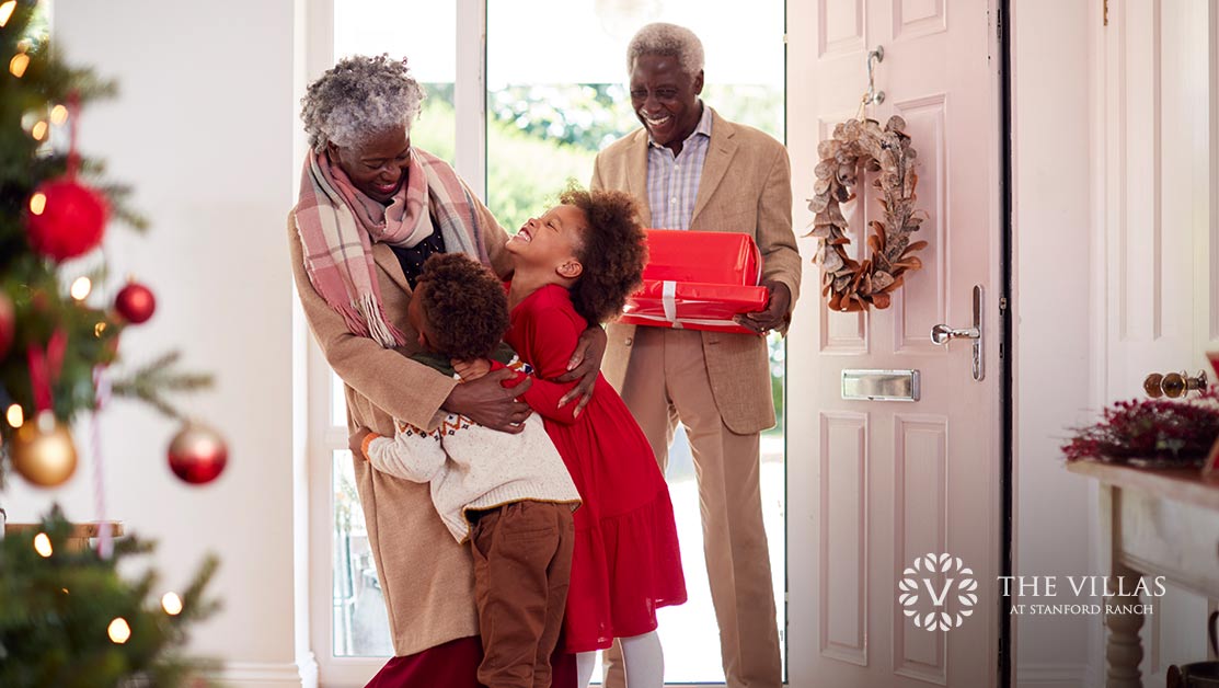 Two grandchildren greet their grandparents at the door with Christmas presents.