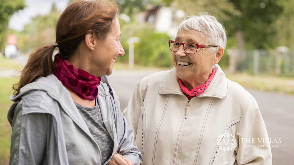 A middle-aged woman walks arm in arm with an elderly woman. Learn how to recognize and overcome caregiver burnout.
