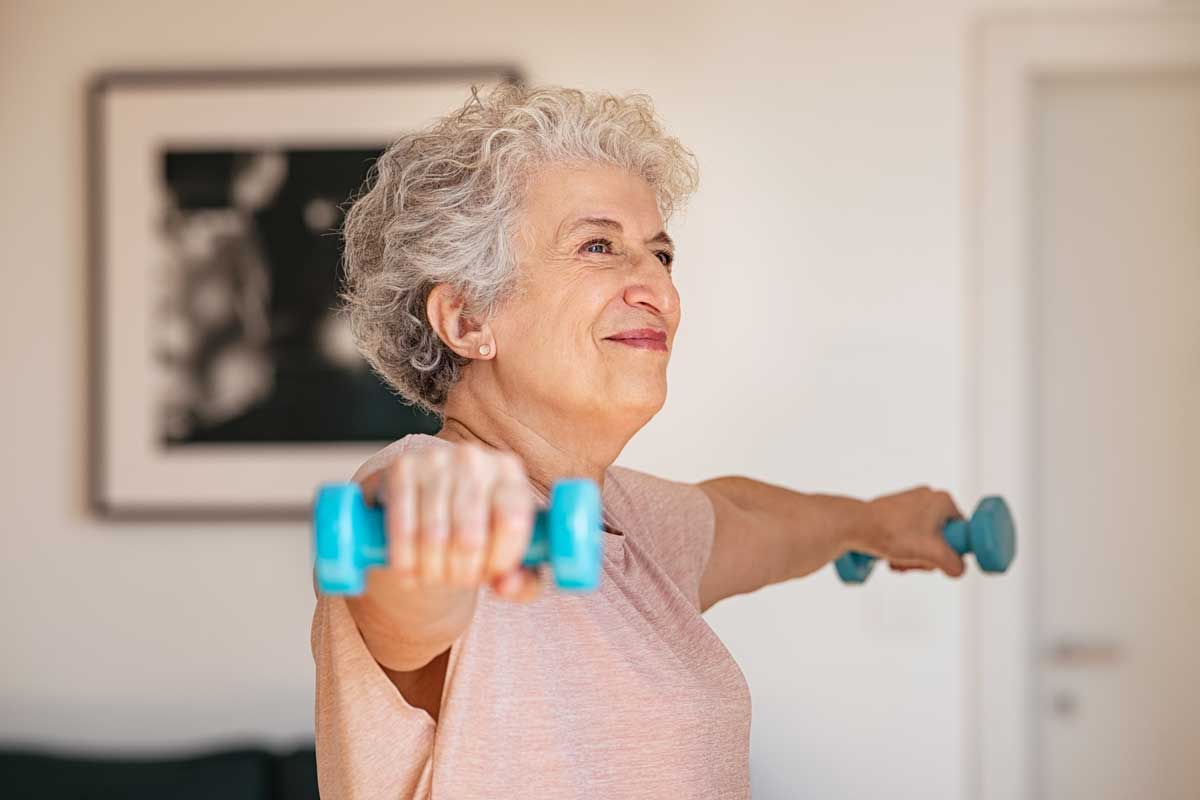 Older woman working out with dumbbells to promote strong healthy bones.