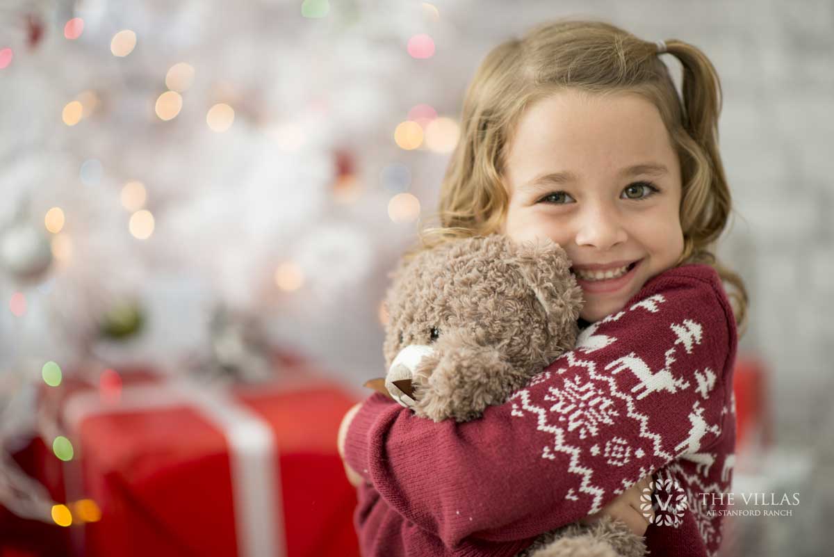 A young girl receives holiday gift. Learn more about our food and toy drive at the Villas at Stanford Ranch.