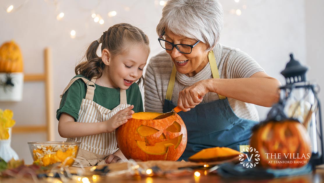 A senior woman and her granddaughter carve pumpkins at Halloween time.